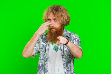 I am watching you. Confident attentive man pointing at her eyes and camera, show I am watching you gesture spying on someone. Handsome disappointed redhead guy isolated on green chroma key background