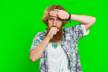 Unhealthy young caucasian man coughing with seasonal flu symptoms covering mouth with hand, feeling sick, allergy, fever or viral infection. Unwell ill guy isolated on green chroma key background