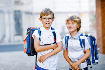 Two little kid boys with backpack or satchel. Schoolkids on the way to school. Healthy adorable...