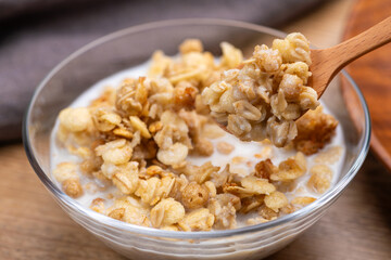 牛乳をかけたグラノーラを木製のスプーンで掬って食べる