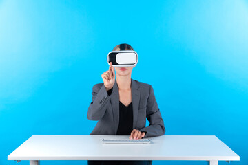 Smart manager wearing VR glasses while sitting at table with keyboard. Businesswoman pointing to...