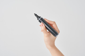 黒いマジックペンを持つ女性の手と白い背景