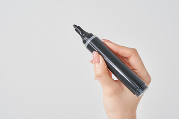 黒いマジックペンを持つ女性の手と白い背景