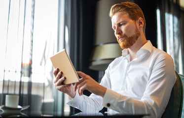 Young modern business man working using digital tablet while sitting in the office