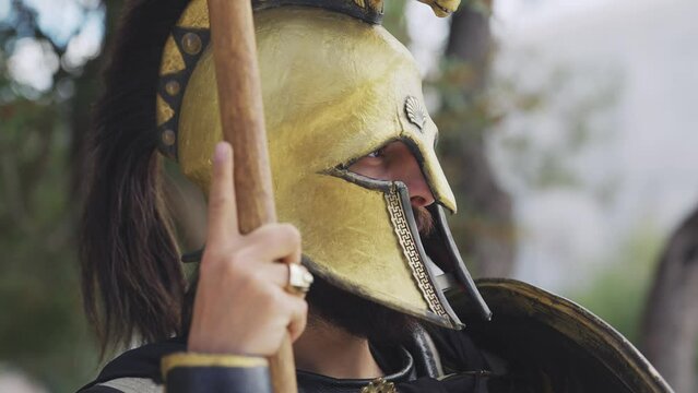 Spartan hoplite warrior posing holding attack spear and protecting with shield at Acropolis in Athens, Greece, cinematic slow motion shot