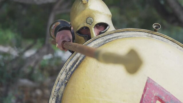 Spartan hoplite warrior going forward in attack with spear and protecting with shield at Acropolis in Athens, Greece, cinematic slow motion shot