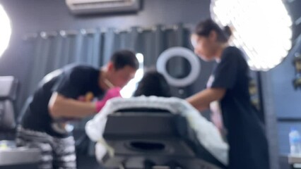 Blurred background tattoo artist making a tattoo for a client at tattoo studio during a bamboo tattoo session.