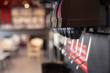 A row of soda dispensers with a red and white sign that says 