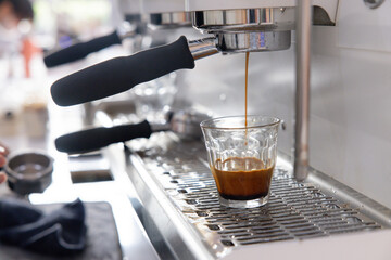 A barista is making coffee with a glass cup