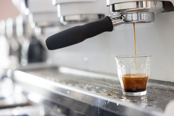 A coffee machine is pouring coffee into a glass