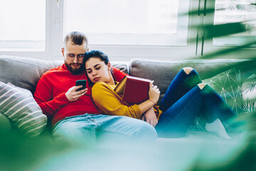Romantic couple in love viewing content from social networks on smartphone spending time at...