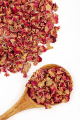 Tea made from tea rose petals in a wooden spoon on white background.