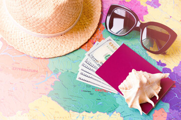 Travel Concept Background. A straw hat, sunglasses, a seashell, a passport and money on a map of...