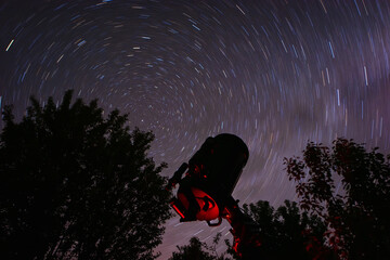 Starry night sky with star trails and an amateur astronomical telescope. Circular star trails...
