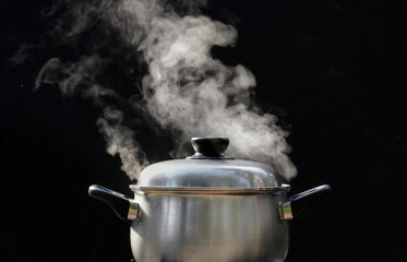 steam over cooking pot in kitchen on dark background