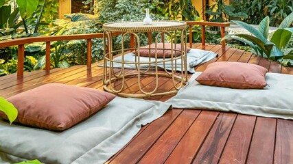 Tranquil sustainable relaxation zone with soft cushions and small table on wooden deck, surrounded...