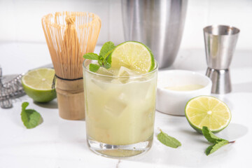 Lime and matcha healthy sour margarita cocktail, iced matcha green tea with citrus and fresh mint, on white background with hard light and bar utensils