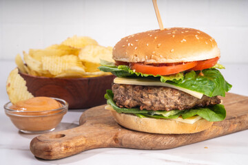 Tasty beef meat burger  with potato chips and burger sauce, Tasty homemade cheeseburger with cutlet, cheese and vegetables, mouth-watering delicious food on white background copy space
