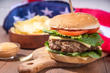 Tasty cheeseburger, chips and sauce with patriotic american flag. July 4th, Independence day picnic...