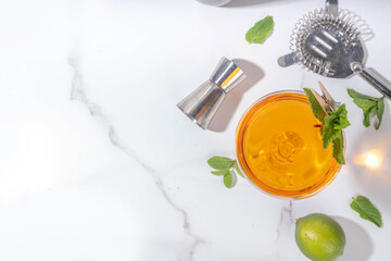 Old cuban alcohol cocktail. Boozy drink with white rum, lime, mint, sparkling wine, sweet and bitter alcoholic drink on white background with hard light and bar utensils