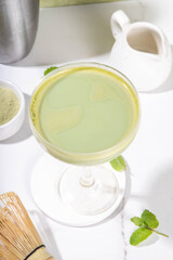 Creamy matcha martini cocktail Matchatini, trendy cold summer cocktail. Matcha non-alcohol mocktail or alcohol cocktail, in martini glasses with green matcha powder, with hard light background