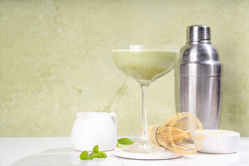 Creamy matcha martini cocktail Matchatini, trendy cold summer cocktail. Matcha non-alcohol mocktail or alcohol cocktail, in martini glasses with green matcha powder, with hard light background