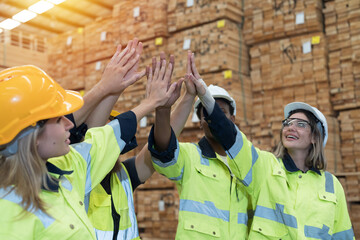 Group of male and female warehouse workers standing putting their hands together in industry...
