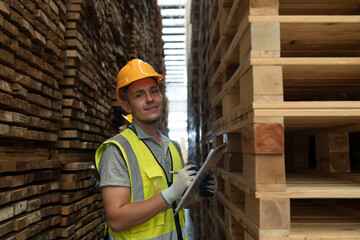 Male warehouse worker working and inspecting barcode of products in wooden warehouse storage. Male...