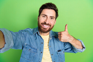 Photo of cheerful positive guy dressed jeans shirt tacking selfie showing thumb up empty space...
