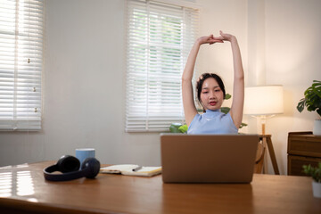 Asian young student doing stretch oneself from study online class. Online distance learning...