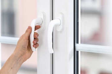 Cropped view of woman hand close pvc door with double glazing on balcony
