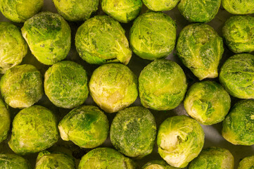 A bunch of green brussels sprouts with some salt on them. The brussels sprouts is frozen and looks...