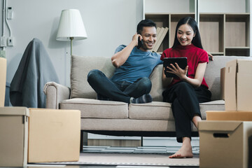 Young couple relaxing sitting on the floor around cardboard boxes at home, smiling happy moving to...