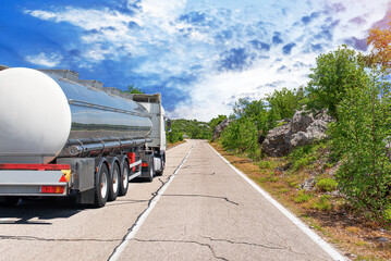 Fuel truck on a picturesque road. A silver tank truck transports fuel.