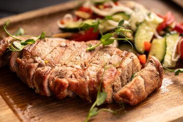 Grilled grilled beef steak with vegetables on wooden board on the table.