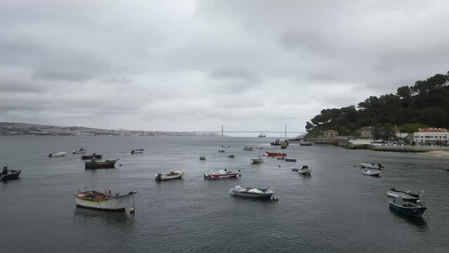 Spectacular drone footage of Trafaria Silopor Harbor captures vibrant maritime activity. Cargo ships unload against the charming coastal town backdrop. Perfect for travel and maritime projects.