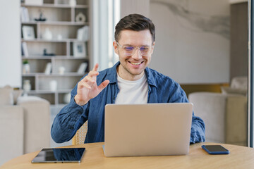 A joyful young professional engagingly communicates during a video call in a modern and stylish living area, expressing satisfaction and confidence.