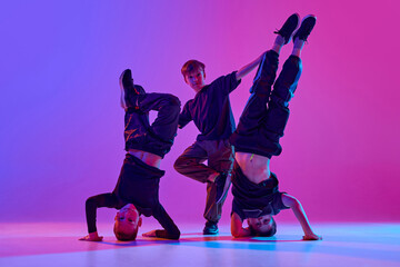 Energetic photo of young boys, in black attire dancing breakdance in motion in mixed neo n light...