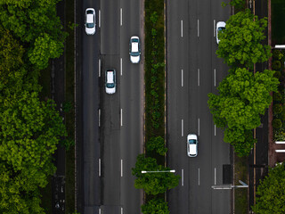 Highway traffic between trees in the early morning. Aerial traffic photo, rush hour infrastructure...