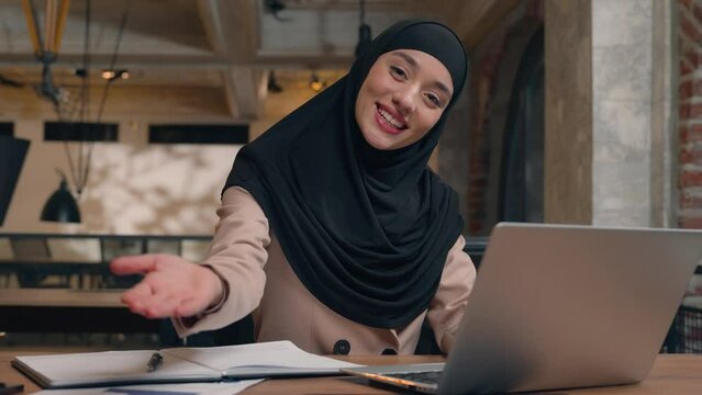 Happy friendly girl Muslim islamic woman in hijab student working laptop at cafe office female Arabian businesswoman business employer lady cheerful smile invite come here welcome gesture invitation