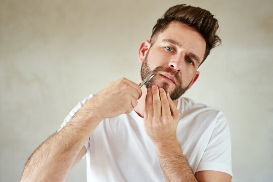 Man, portrait and scissors in home bathroom for grooming, skincare or morning routine for wellness. Face, trim beard or serious person cleaning for beauty, health or hair removal for hygiene in house