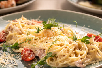 Spaghetti Carbonara with bacon and cheese on blue plate, close-up. Italian restaurant kitchen menu
