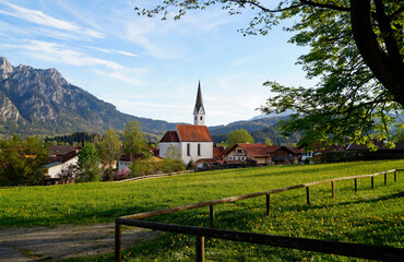 a scenic alpine view with lush green alpine meadows and an old church in the alpine village...