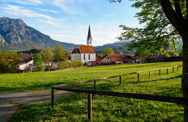 a scenic alpine view with lush green alpine meadows and an old church in the alpine village...