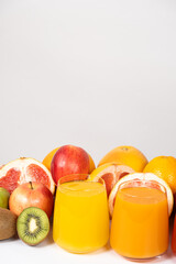 Orange and multifruit juices in glasses on white background with space for text