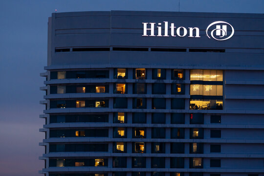 KUALA LUMPUR, MALAYSIA - JULY 16, 2023: Hilton hotel logo is illuminated against the blue hour, with some room lights shining to indicate occupancy.