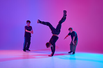 Neon dance battle. Dancer performing impressive headstand, breakdance moves in mixed neon light...