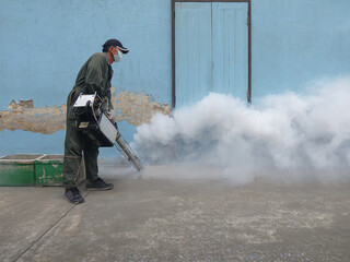 A man sprays chemical fog to kill Aedes mosquitoes. Causes of dengue fever