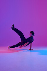 Young boy, dancer in motion performing an energetic street dance in mixed neon light against vibrant gradient background. Concept of sport and hobby, music, fashion and art, movement. Ad
