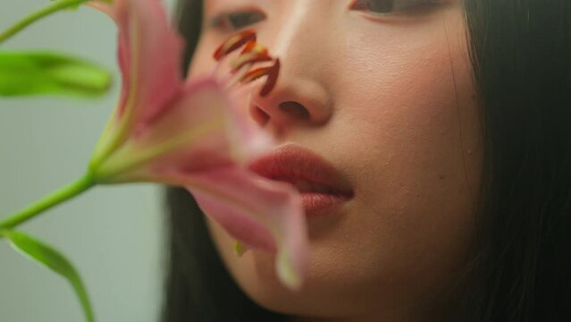 Asian Korean Woman Young Female Smelling Lily Flowers Enjoy Inhale Natural Scent Sensual Tenderness. Close Up Chinese Girl Purity Face Smell Fresh Spring Flower Buds Aroma Blossom Plant Beauty Health